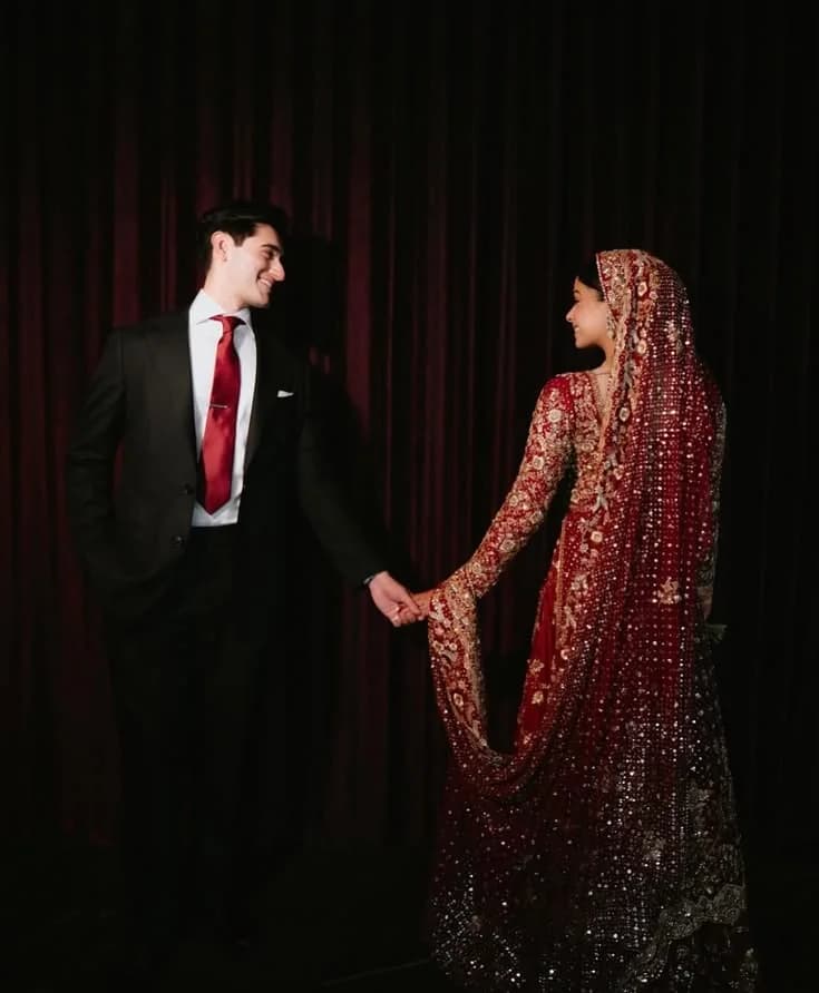 The bride and groom sitting together, her hand in his